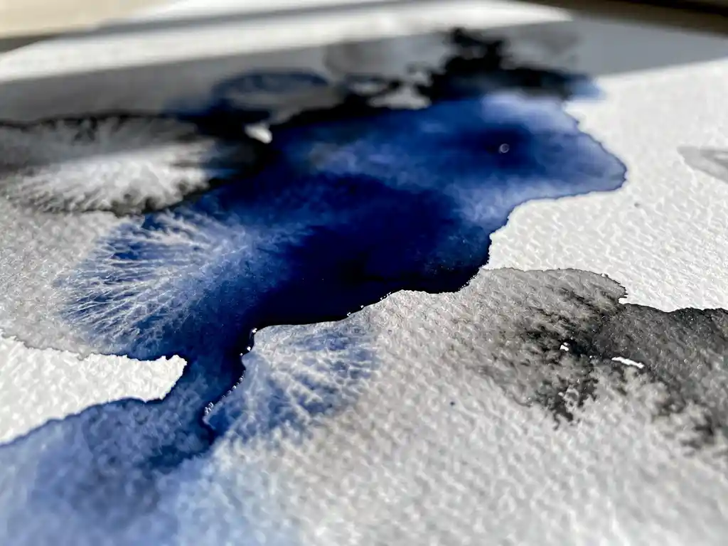 Macro close-up van kobaltblauwe aquarelverf die vloeit over nat getextureerd papier met grijze uitwassingen