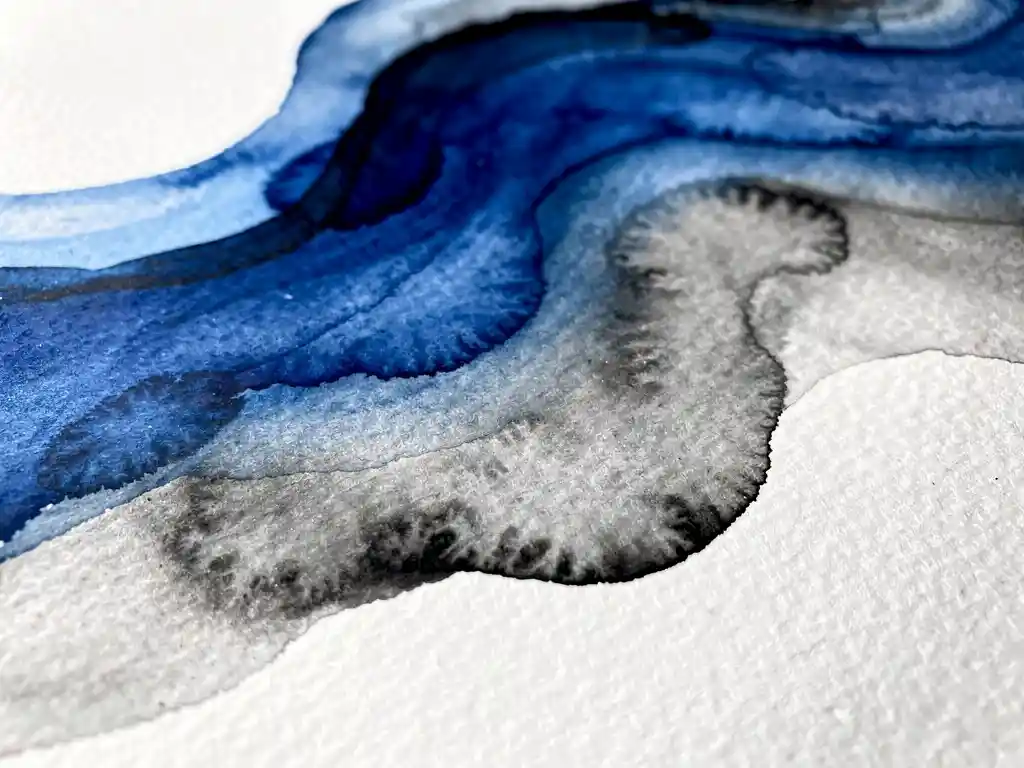 Abstracte aquarelverf in diepblauw die overvloeit in grijze tinten op wit papier met natuurlijke pigmentverspreiding