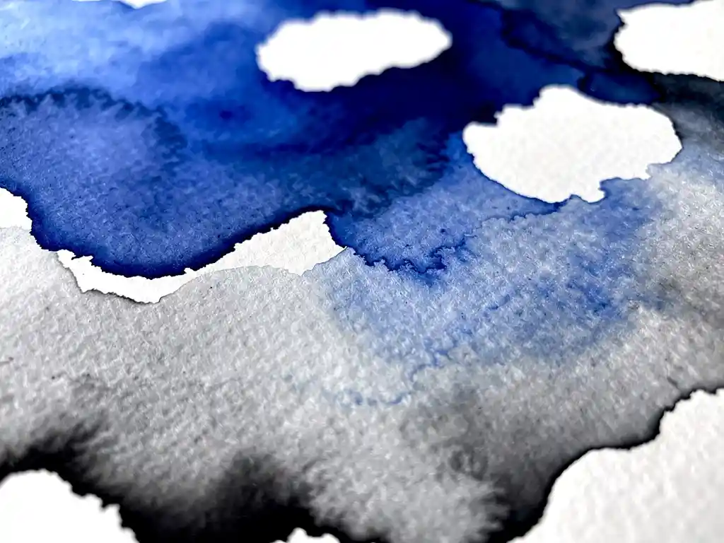 Vloeiende aquarelverf in elektrisch blauw met grijze verlopen en witte wolkvormige ruimtes op gestructureerd papier