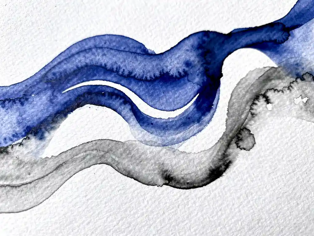 Abstracte aquarelverf in kobaltblauw en houtskoolgrijs vloeit over wit papier met natuurlijke kleurovergangen