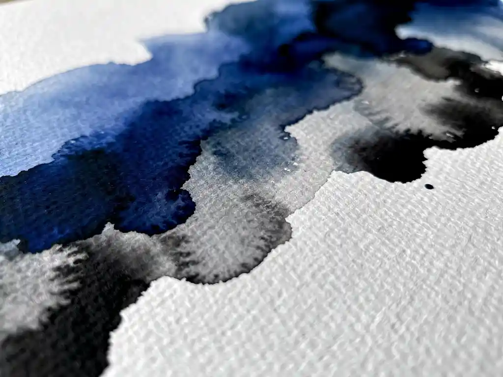 Abstracte aquarelverf in kobaltblauw en grijs vloeit over gestructureerd wit papier met zwarte accenten