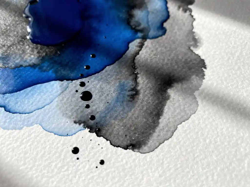 Kobaltblauwe en grijze aquarelverf vloeit organisch over wit papier met natuurlijke schaduwen en korrelstructuur