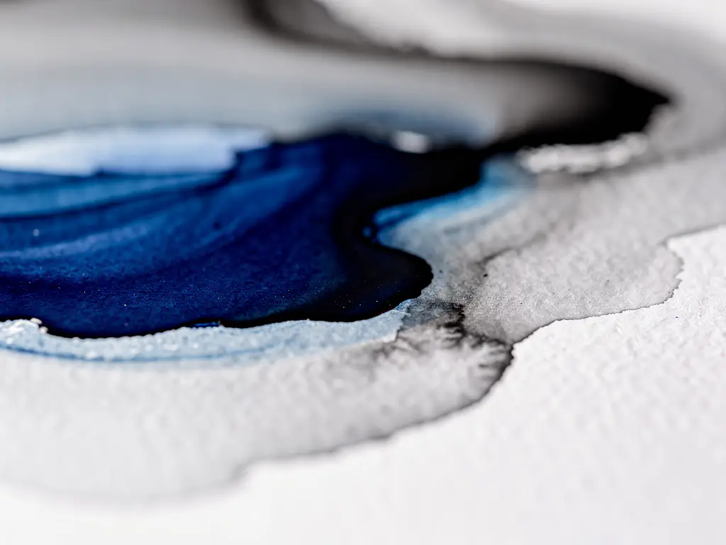 Vloeiende aquarelverf in diep kobaltblauw en grijs op wit papier met zwarte accenten, macro-opname van organische kleurovergangen