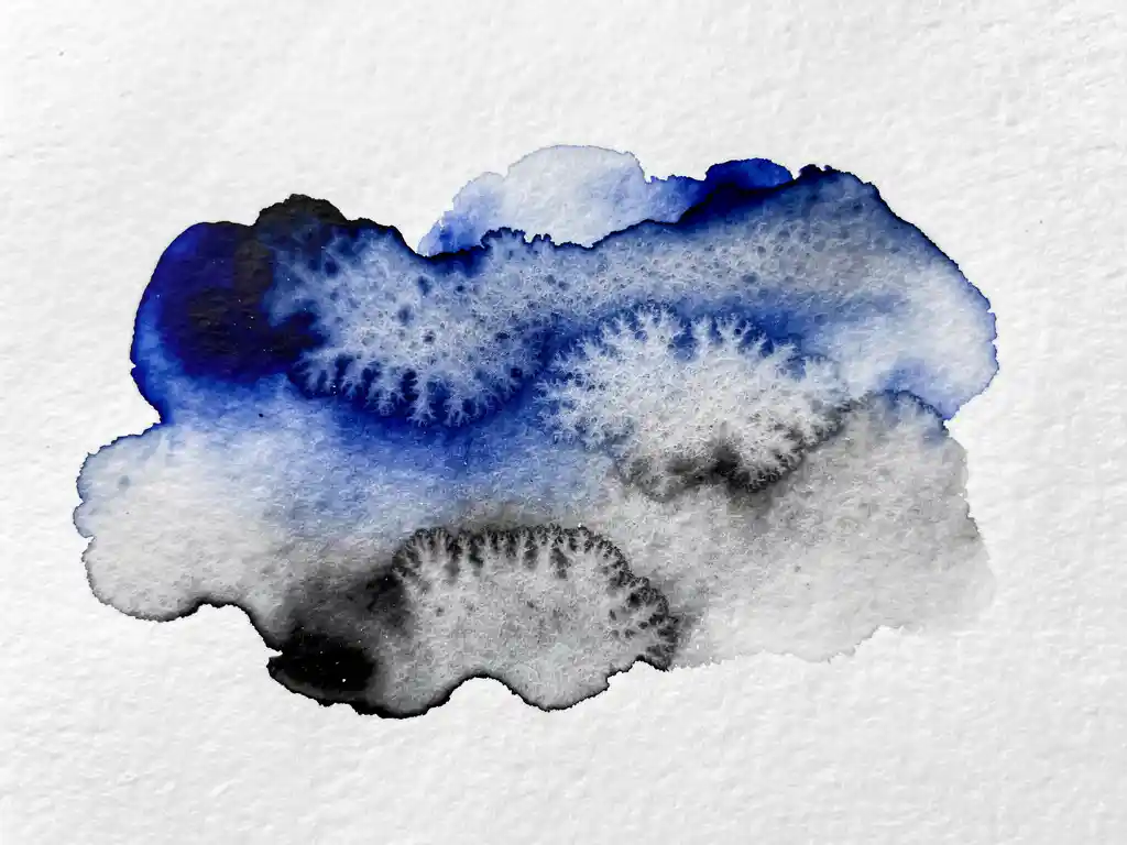 Waterverf inkt vloeit over wit papier met kobaltblauwe en grijze tinten die organische wolkvormen creëren