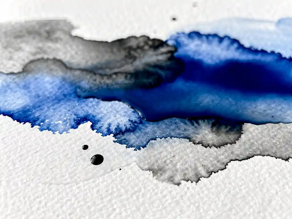 Macro-opname van kobaltblauwe aquarelverf die vloeit over getextureerd wit papier met grijze wassen en organische patronen