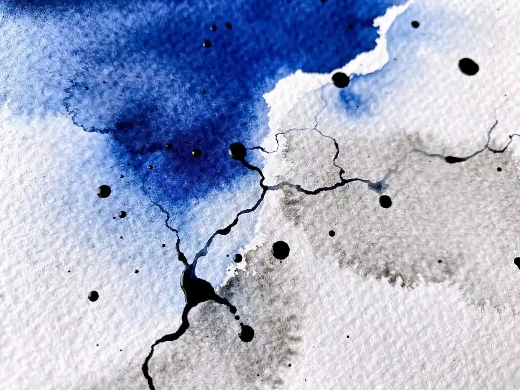 Elektrisch blauwe aquarelverf vloeit in grijze tinten over wit papier met zwarte inktdruppels in abstracte compositie