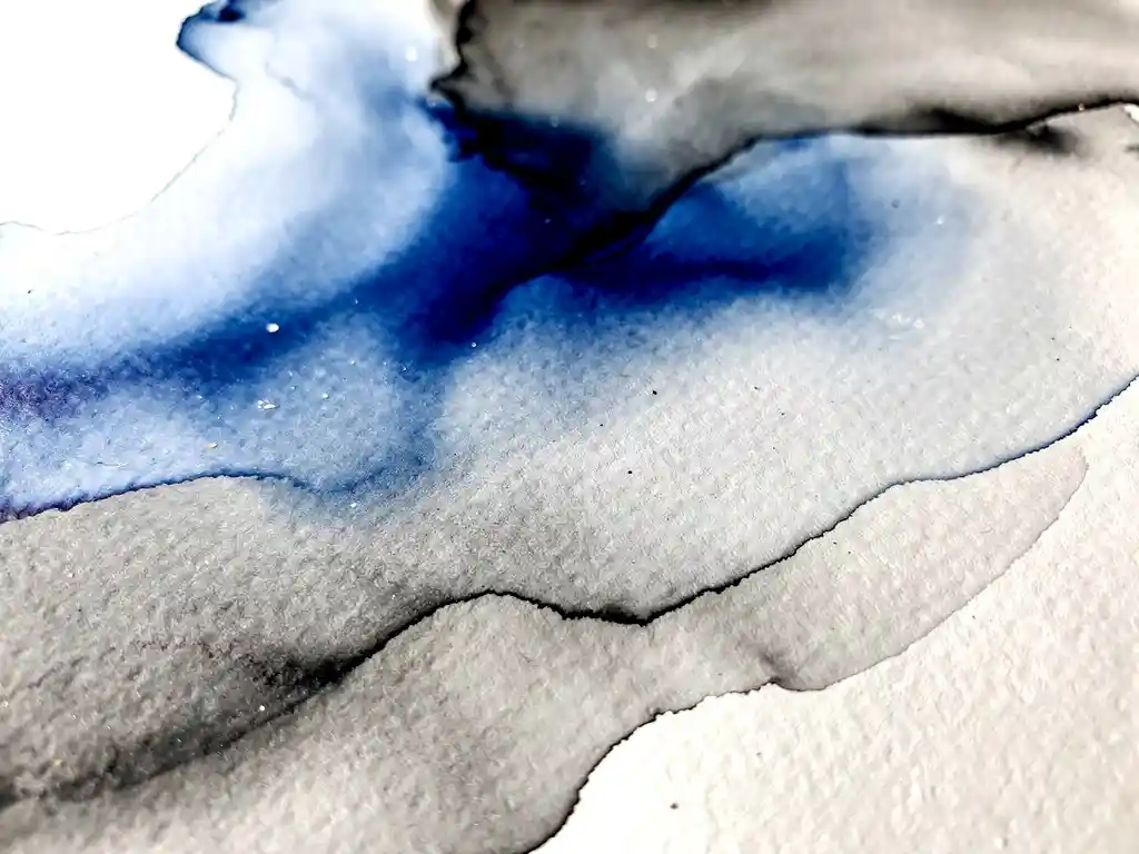 Aquarel verf in diep kobaltblauw vloeit over gestructureerd papier met grijze overgangen en witte negatieve ruimte
