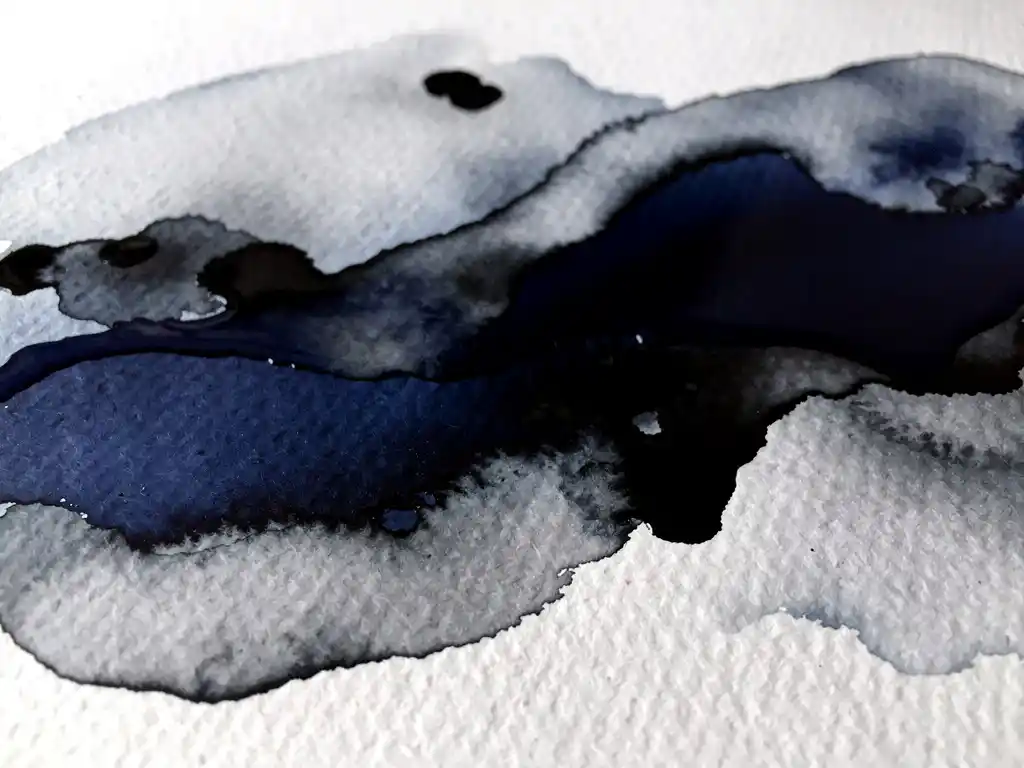 Donkerblauwe aquarelverf vloeit in grijze tinten op gestructureerd wit papier met zichtbare korrel en natuurlijke abstracte vormen