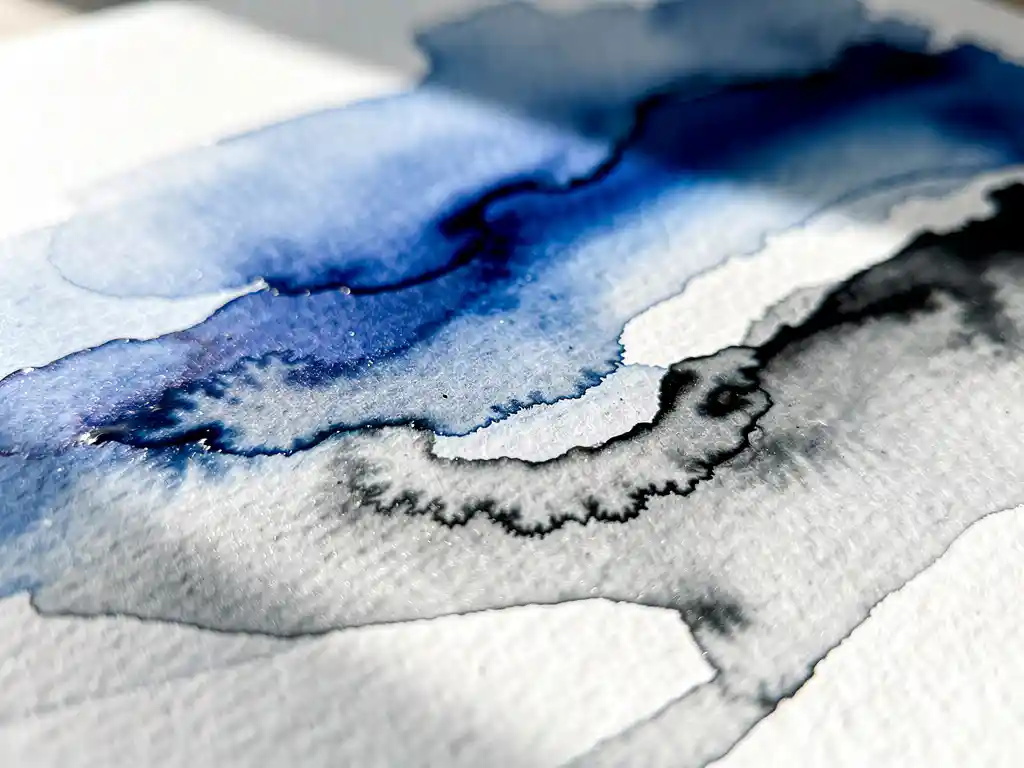 Macro close-up van kobaltblauwe aquarelverf die vloeit over wit papier met grijze uitwassingen en organische texturen