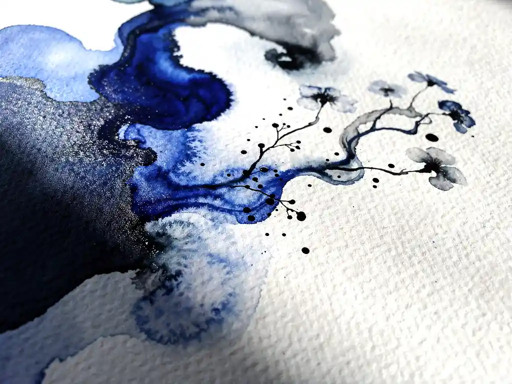 Koninksblauw aquarelverf vloeit over wit papier met zwarte inktdruppels en natuurlijke kleurovergangen