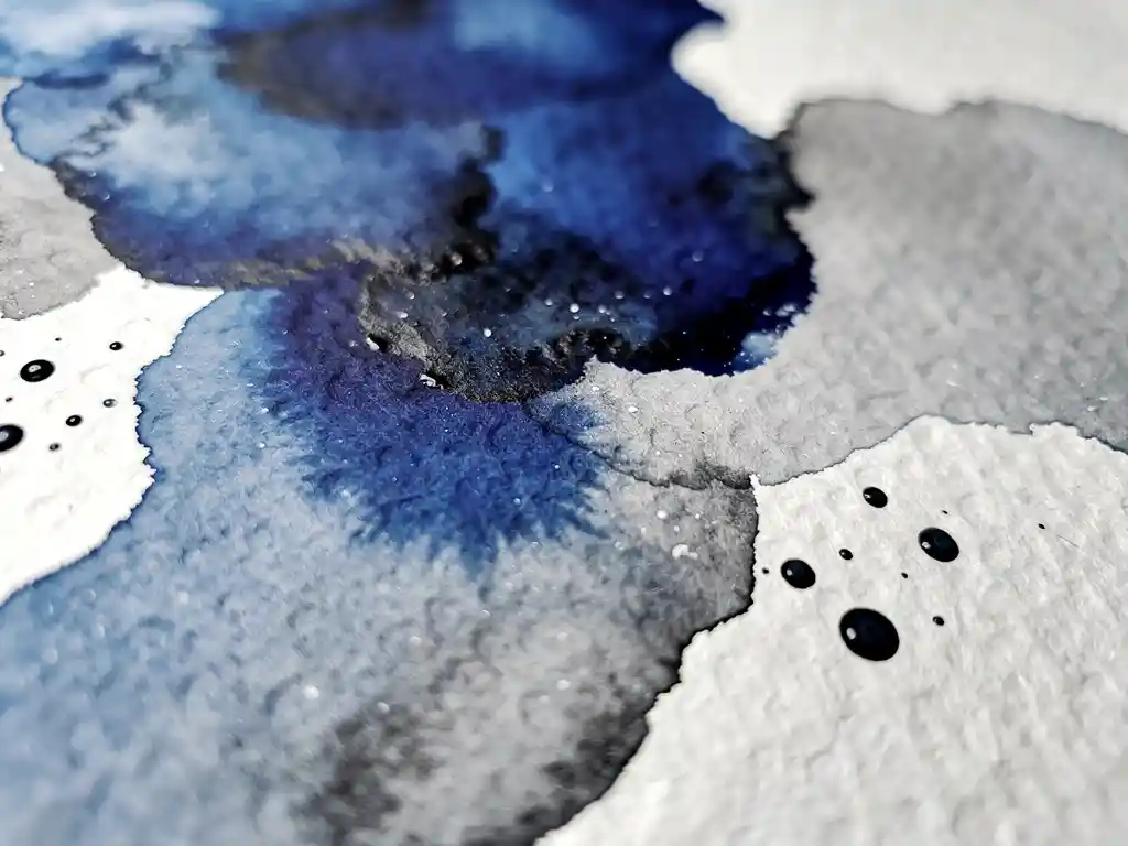 Vloeiende aquarelverf in diep kobaltblauw en grijs op gestructureerd papier met zwarte inktdruppels en witte negatieve ruimte